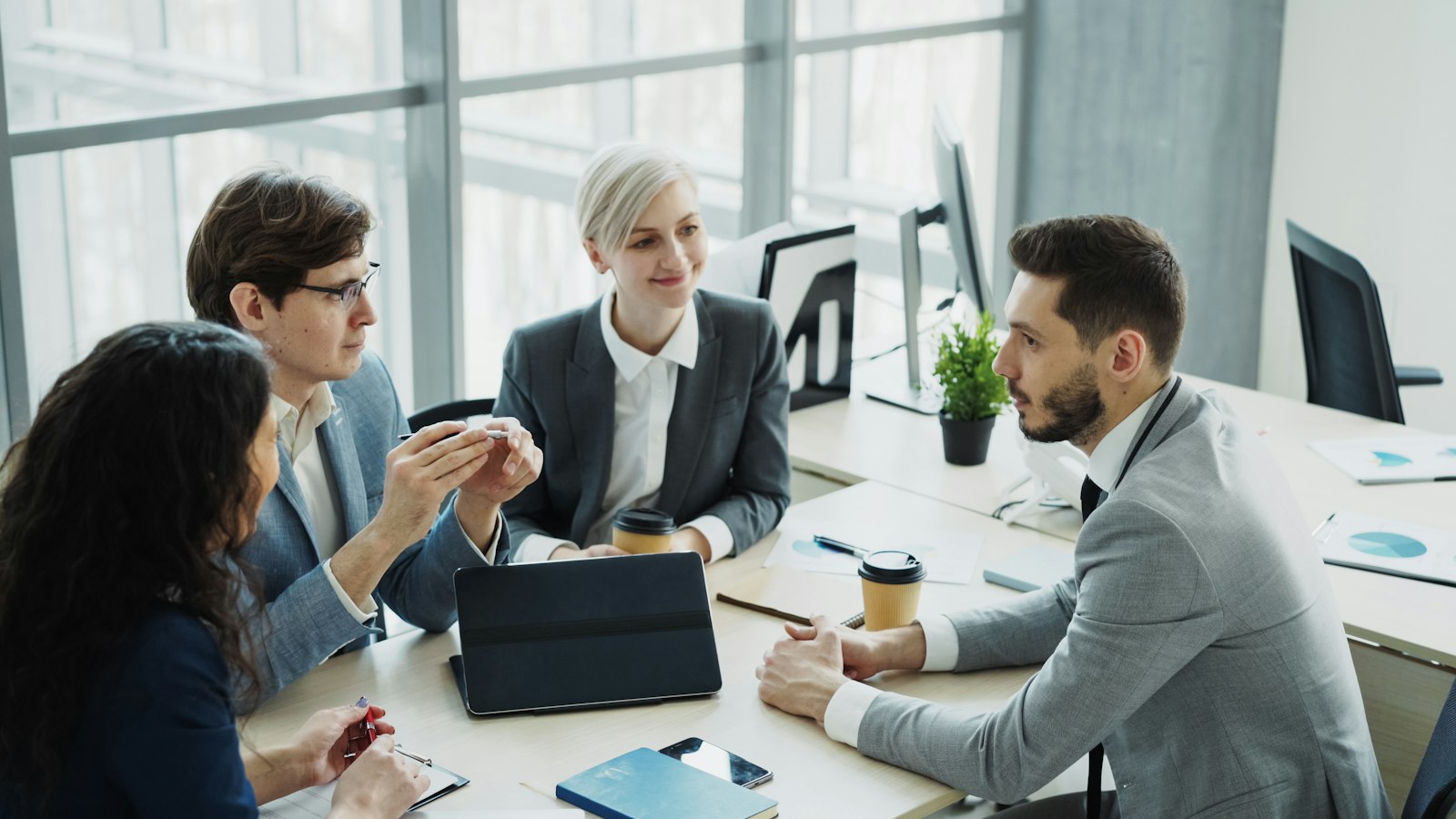AI Act : ce qui change vraiment pour une PME après l'Omnibus 2 Quatre personnes en réunion autour d'une table avec tablette et ordinateur portable dans un bureau lumineux