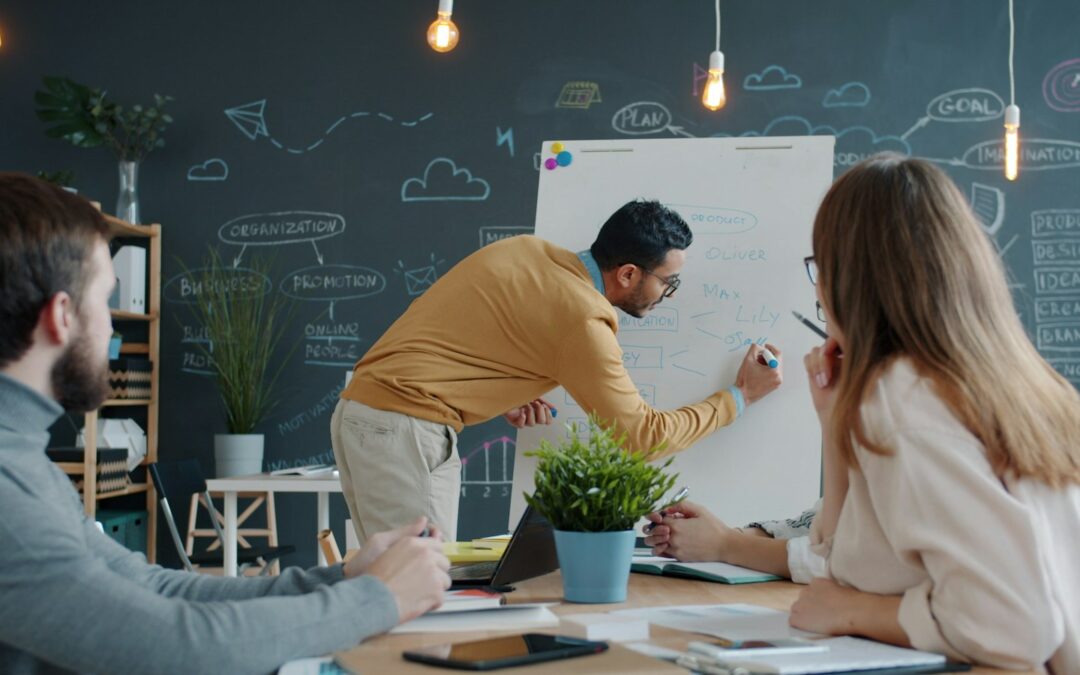 Formateur expliquant la formation IA en entreprise sur un tableau blanc devant deux collègues