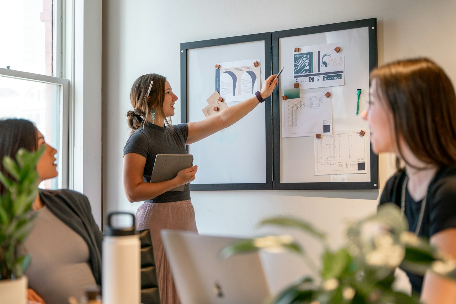 Formation IA en entreprise : former ses équipes en 4 étapes (et financer) 3 Formatrice présentant un tableau d'affichage à une collègue lors d'un atelier en bureau