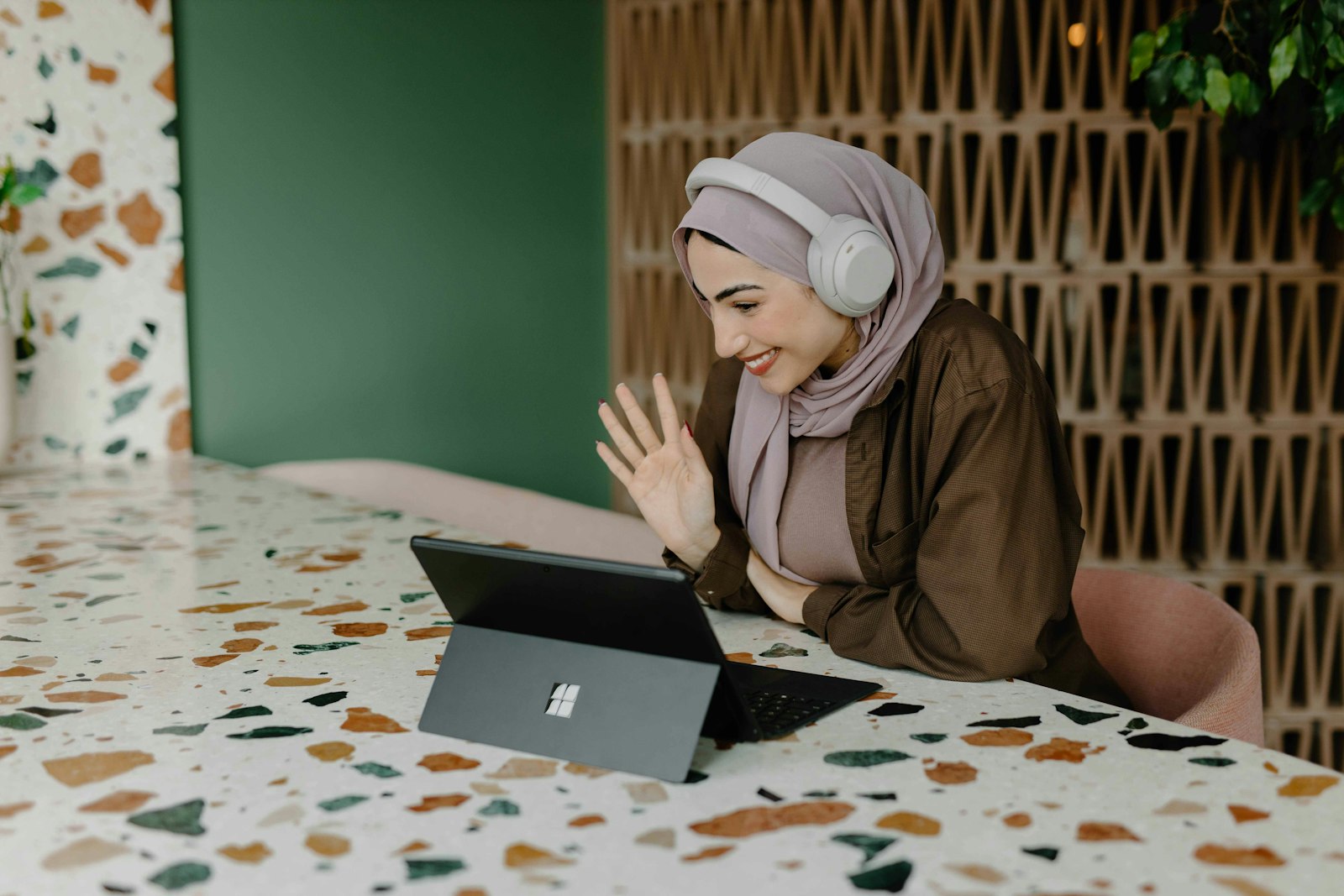 Participante souriante avec un casque audio saluant de la main devant sa tablette pendant la formation